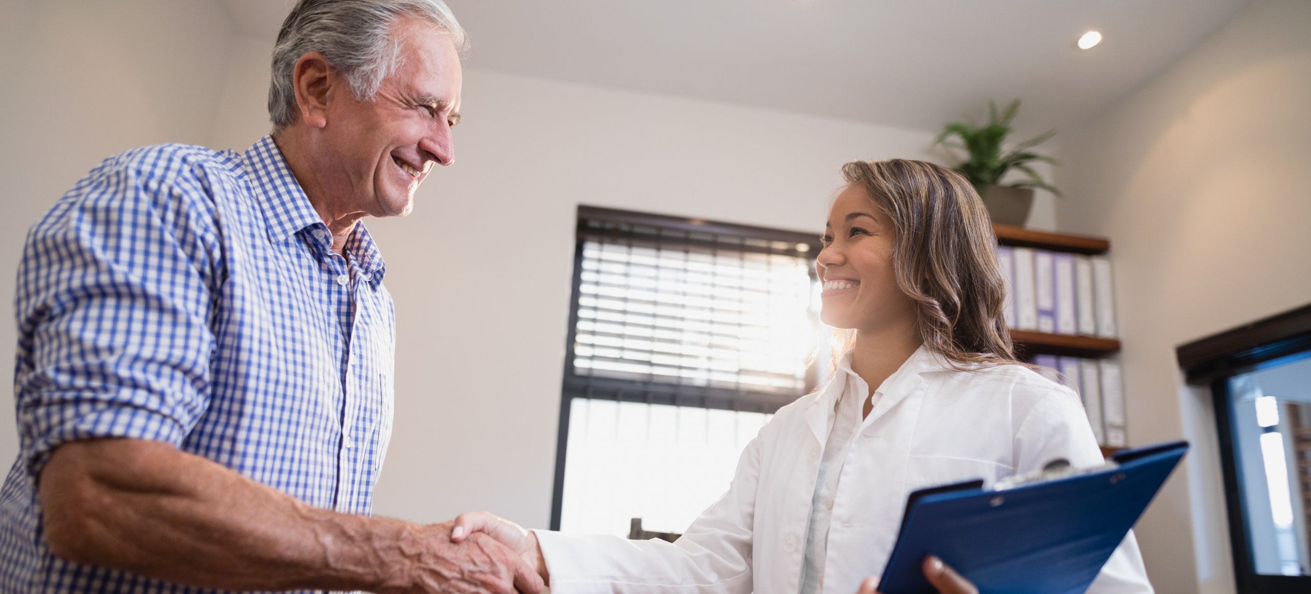 Smiling senior male patient and female therapist shaking hands